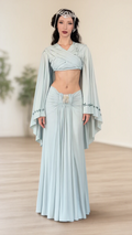 Front full-length view of model wearing light blue fantasy capelet crop top and ruched maxi skirt set