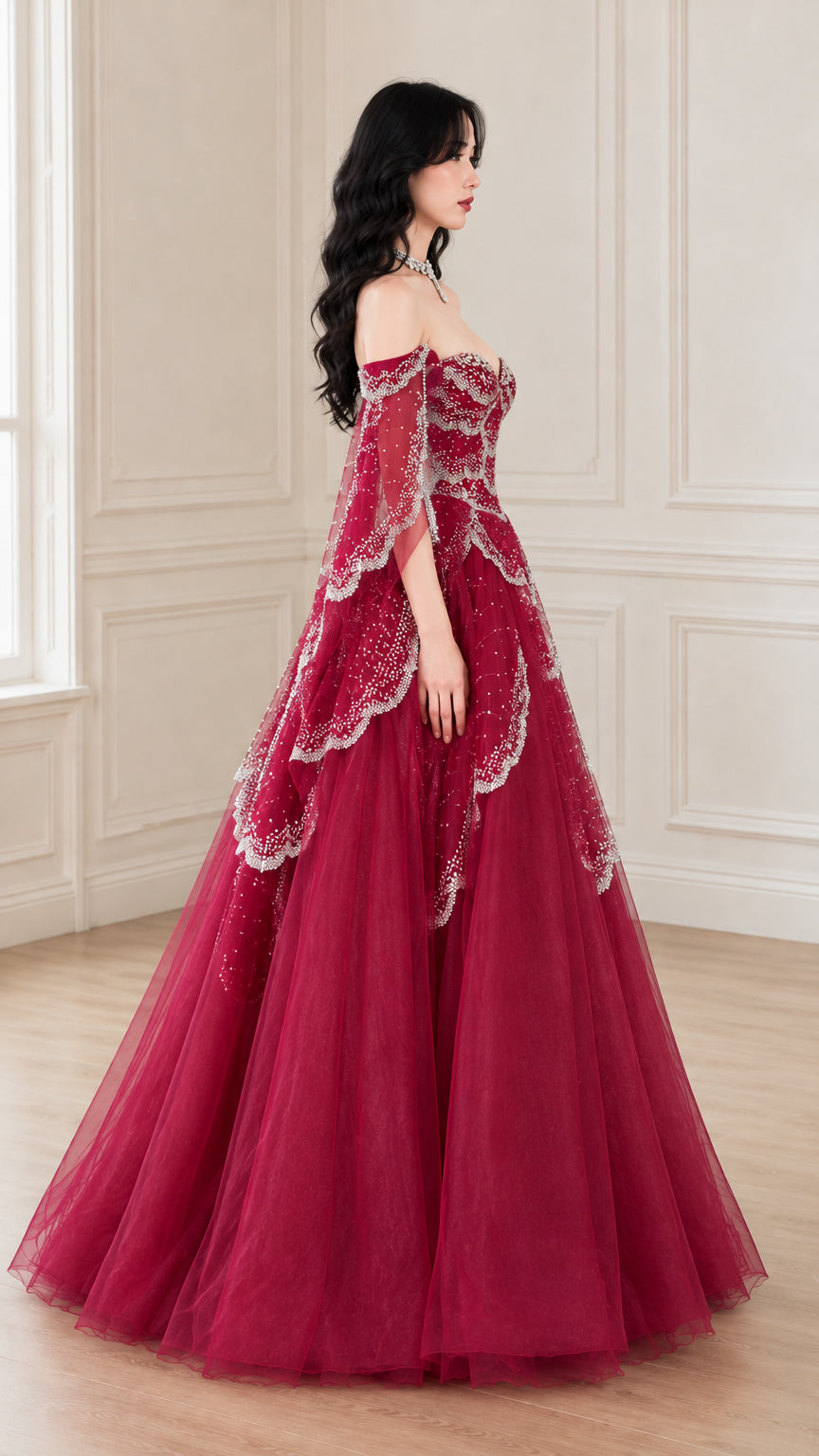 Side profile view of woman wearing burgundy off-the-shoulder tulle ball gown