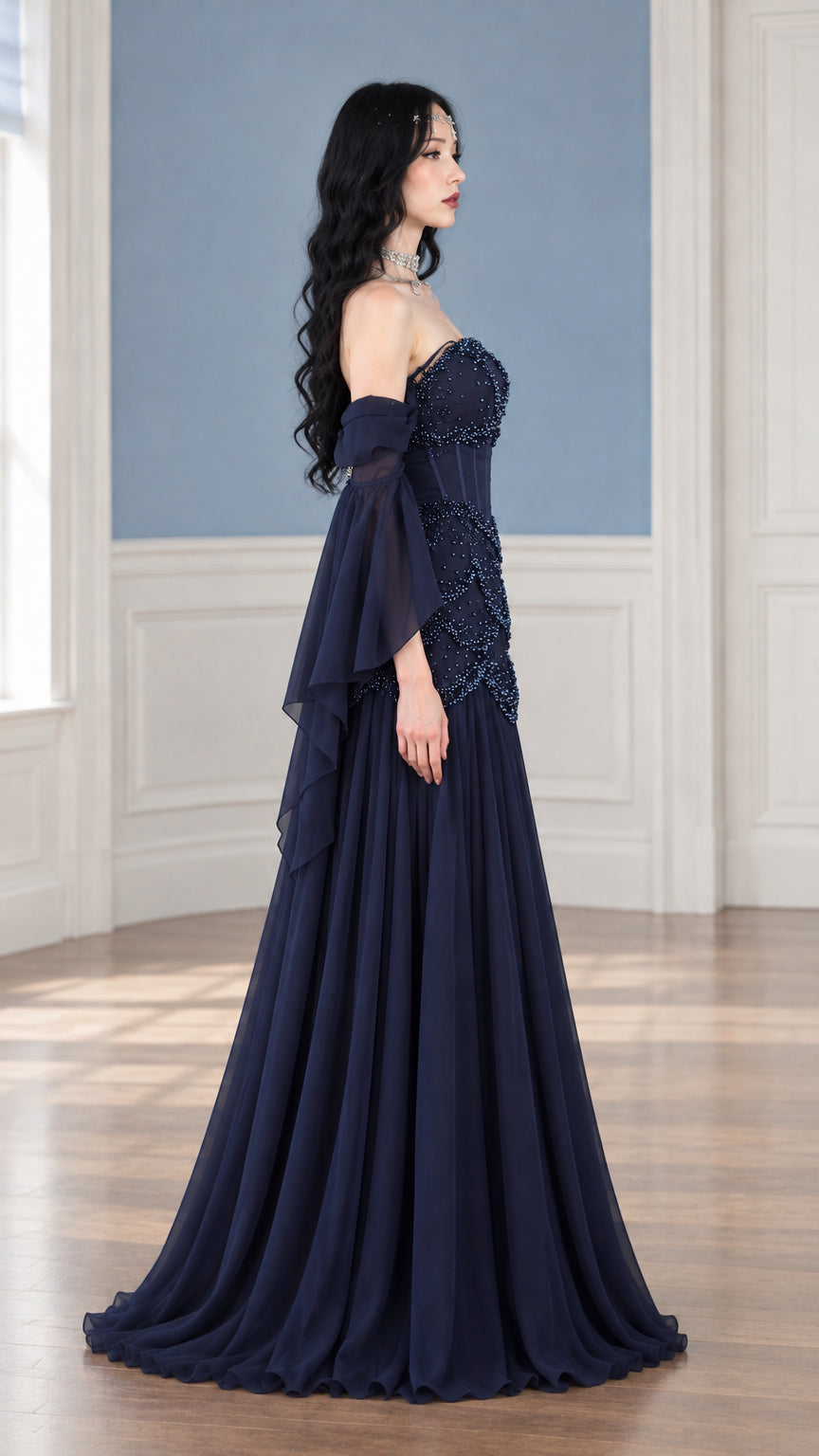 Side profile of navy blue strapless beaded corset maxi dress with flowing train