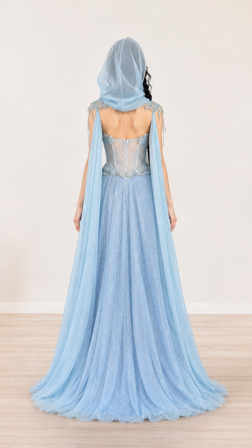 Back view of model in light blue hooded gown showing open-back detail and flowing train