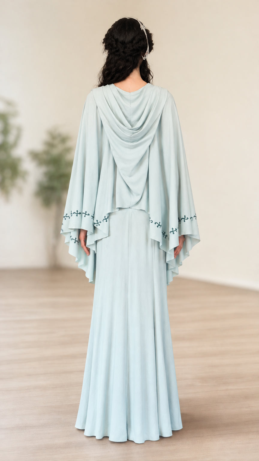 Back view of light blue two-piece set showing cowl hood drape and flowing cape sleeves