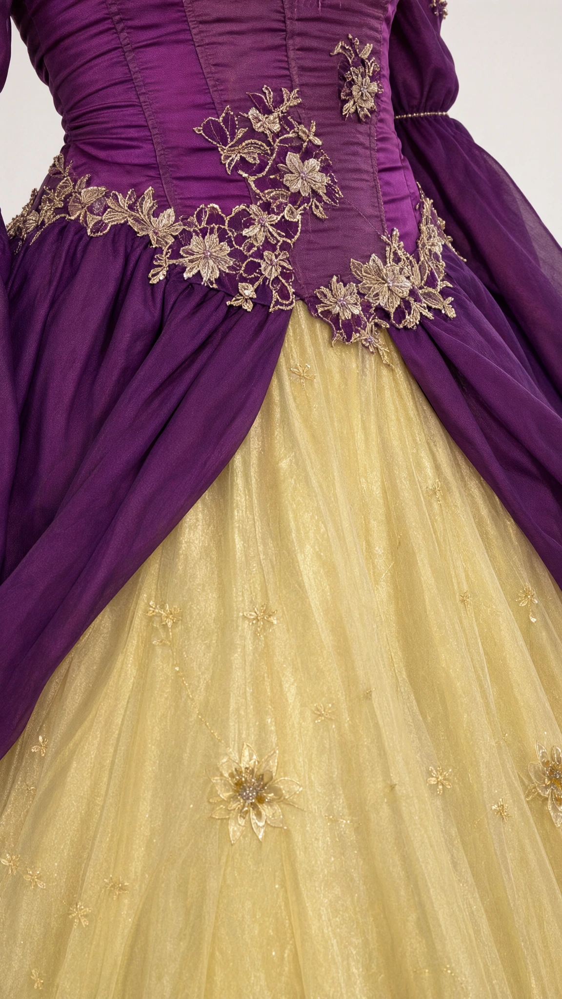 Close-up of intricate floral embroidery and draped peplum detail on purple and gold ball gown