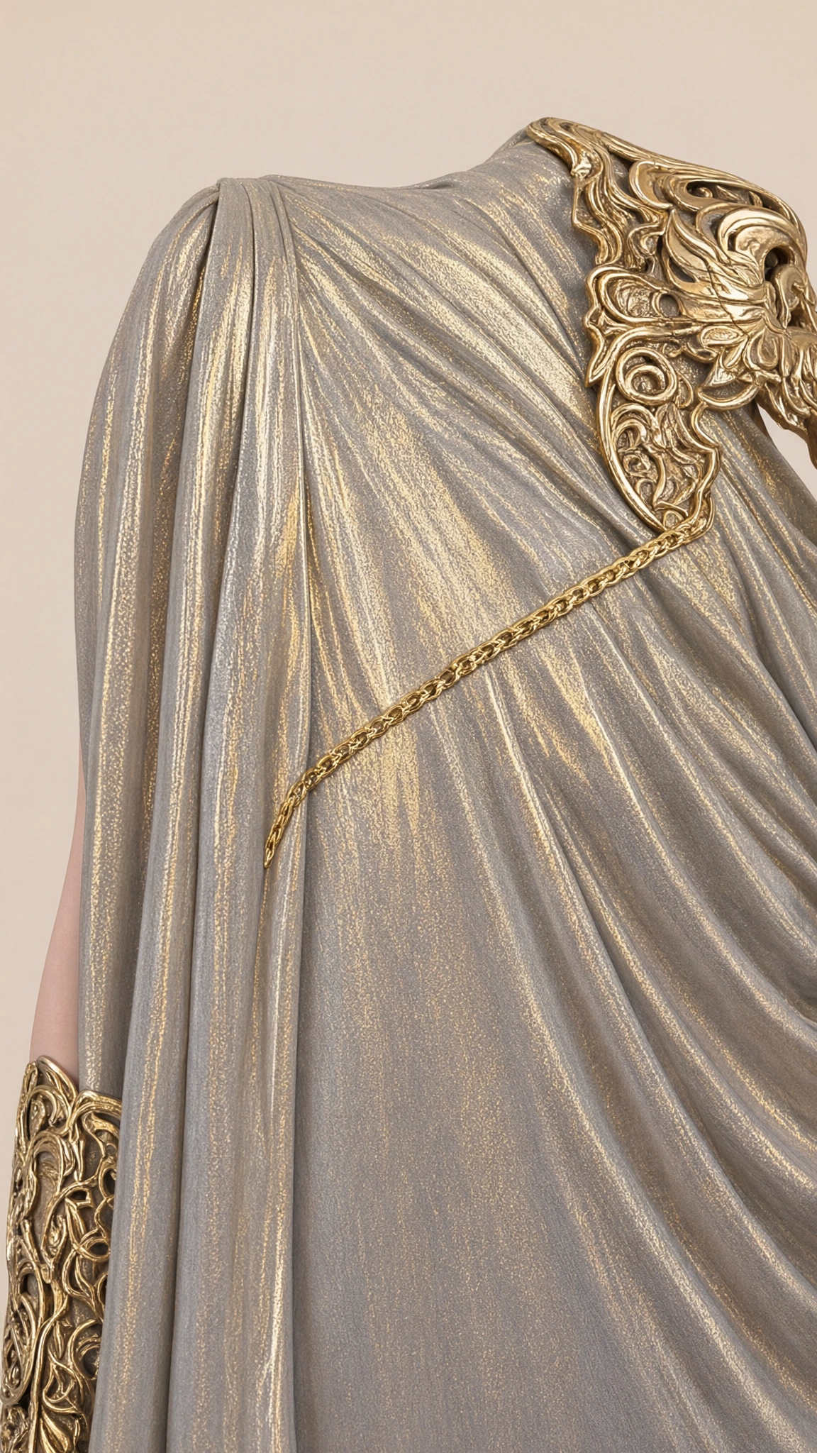 Close up of shimmering metallic fabric draping and ornate sculpted gold shoulder accent